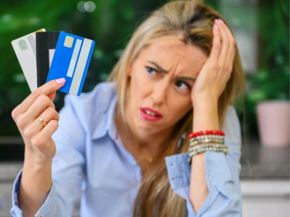 A women looking at a handful of credit cards with a stressed expression